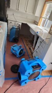 A kitchen is being cleaned with a vacuum and a blower.