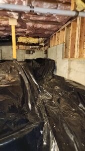 A black tarp covering the floor of a basement.